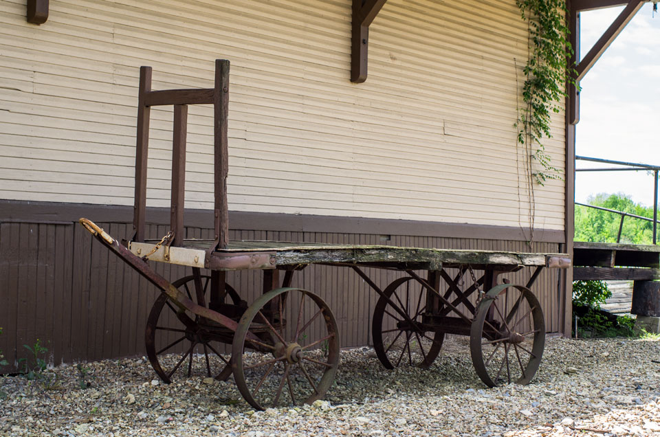 An old freight wagon waits in the shadow of the empty depot. 